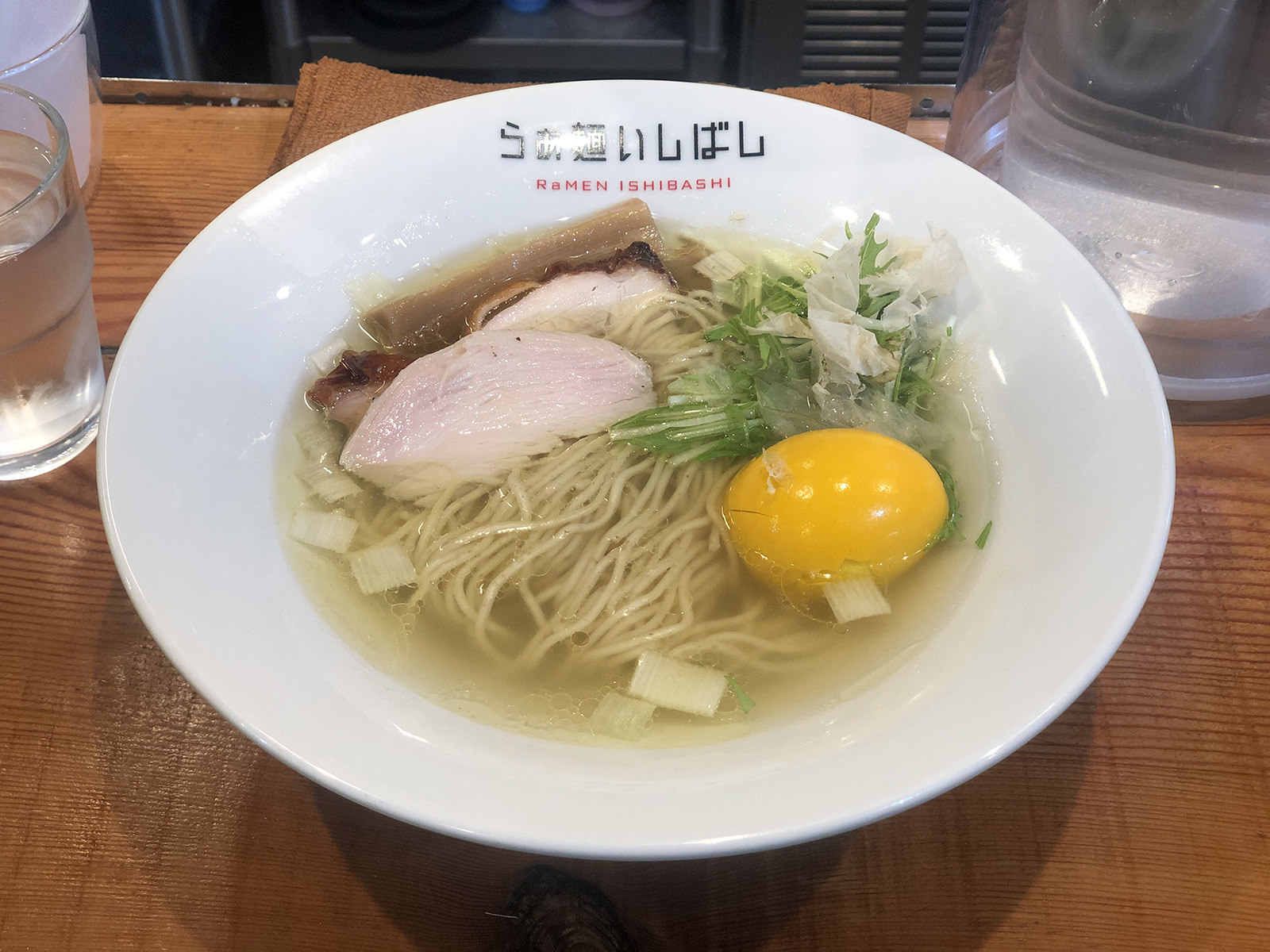 黄色い味玉・三つ葉・鶏節・2種類のチャーシュー・太いメンマが乗り、角切りのネギが浮かんだ、澄んだ色のスープの塩ラーメン