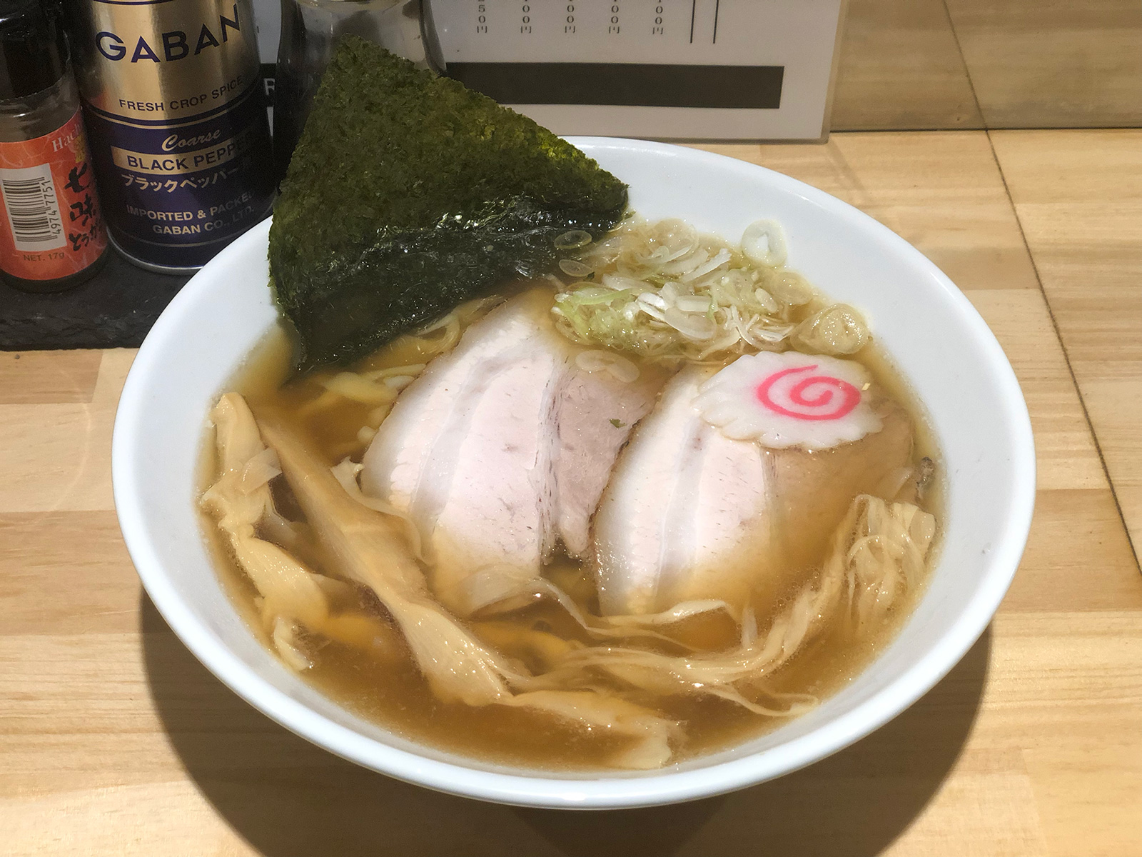 チャーシュー2枚・海苔1枚・ナルト・穂先メンマ・輪切りネギが乗った、茶色の澄んだスープのラーメン